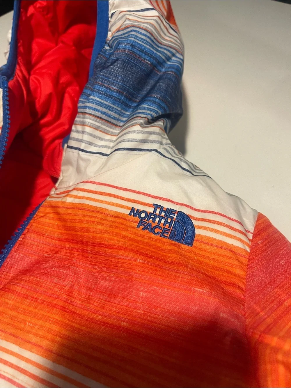 The North Face reversible Solid Red or Vibrant Striped side Puffer Jacket.
